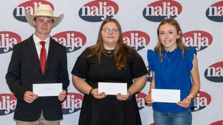 Three young people stand side by side in front of a backdrop with the nalja logo, each holding a white envelope. The person on the left wears a suit and cowboy hat, the center wears a black dress, and the right wears a blue blouse.