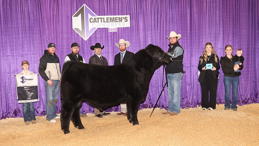 A group of people stand around a black steer at the Cattlemen's Congress 2024, with a purple backdrop and a sign displaying the event's name.